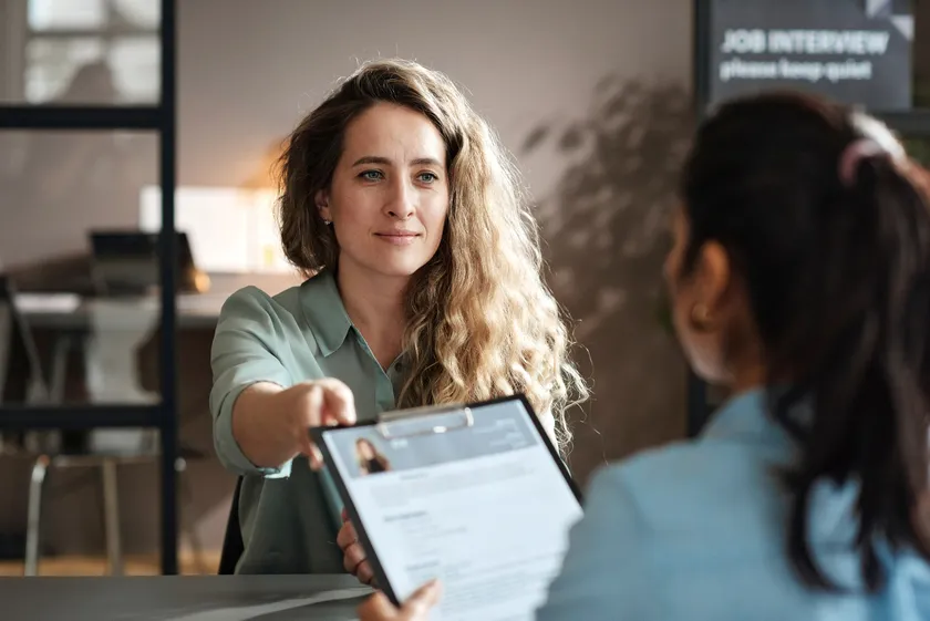 Job candidate handing her CV to an employer at an interview