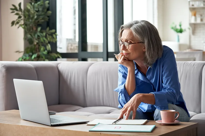 Woman thinking over a programme with a laptop on the sofa