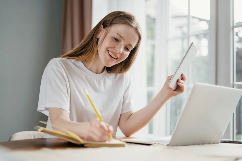 Smiling young woman studying at home with a tablet