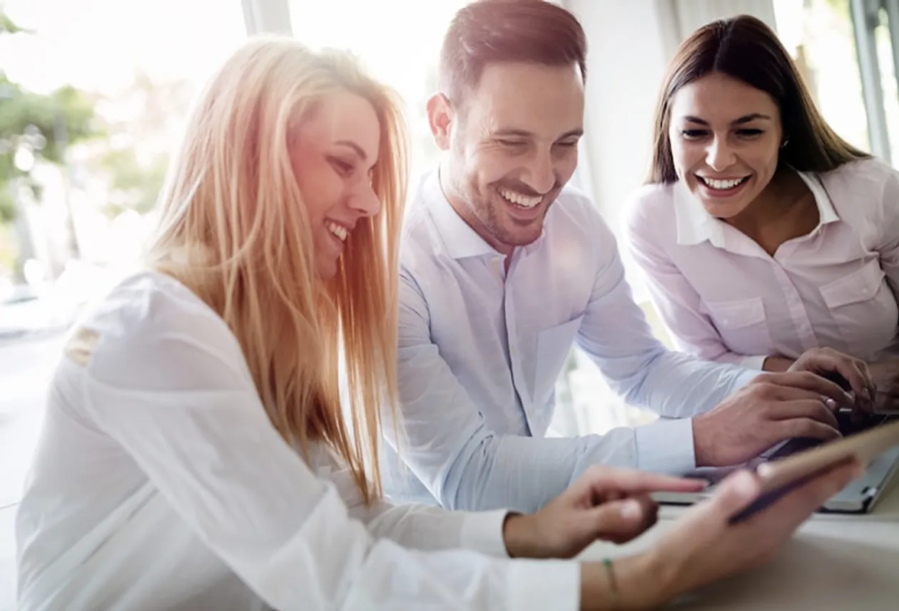 Three cohort members working together on a laptop